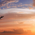 Woman raising her arms at sunrise.